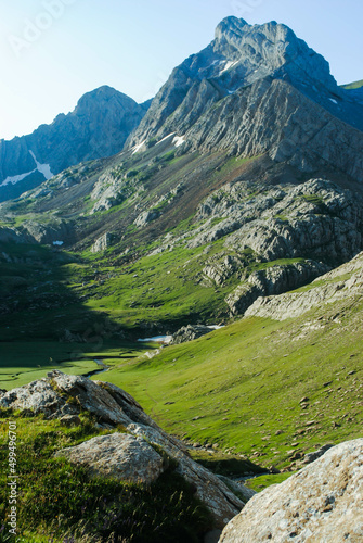 Green hill full of nature and rocks in a mountainous landscape with blue and clear skies