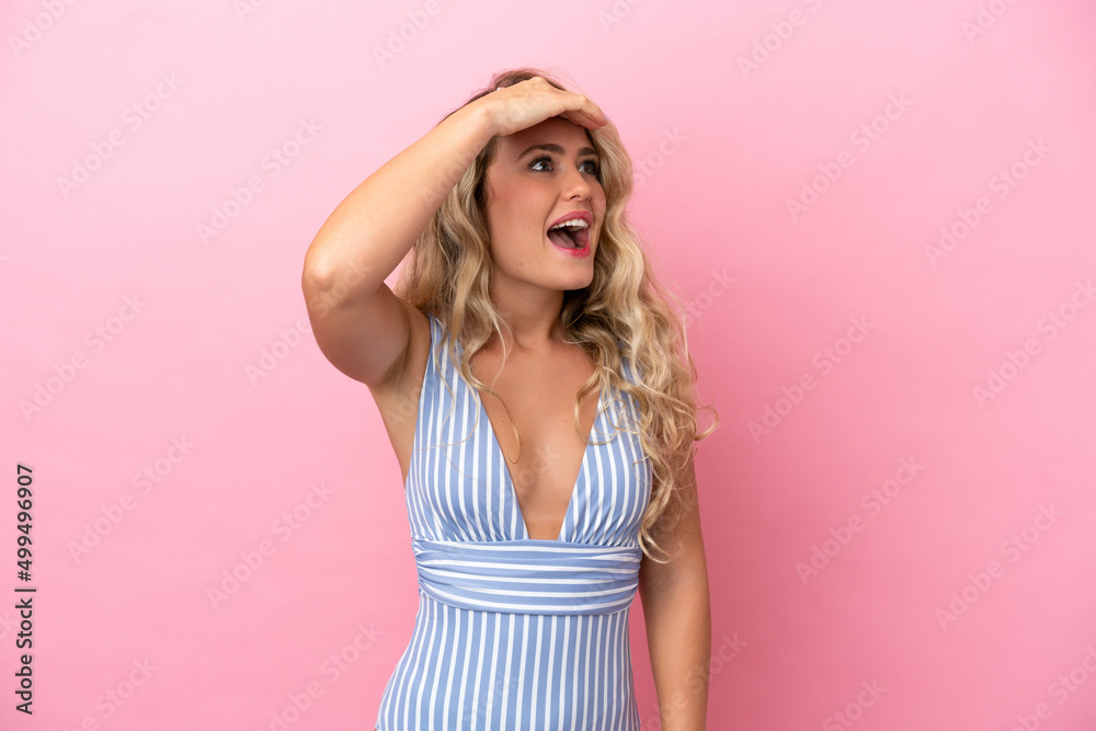 Young Brazilian woman in swimsuit in summer holidays isolated on pink background doing surprise gesture while looking to the side Young Brazilian woman in swimsuit in summer holidays isolated on pink background doing surprise gesture while looking to the side