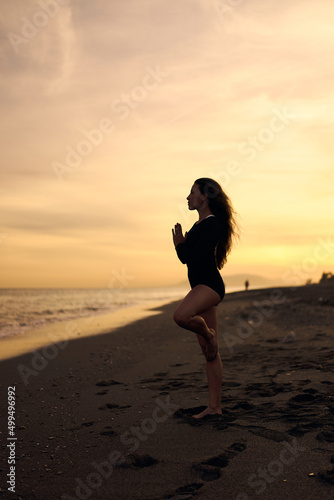 woman doing a yoga practice at the beach while a beautiful sunset