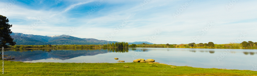 Mountain landscape reflected in the water of a lake on a sunny day. Copy space. Selective focus.