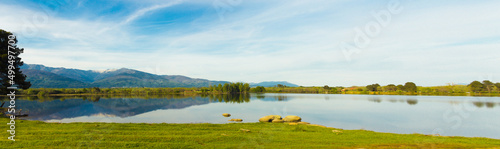 Mountain landscape reflected in the water of a lake on a sunny day. Copy space. Selective focus. © Rodrigo
