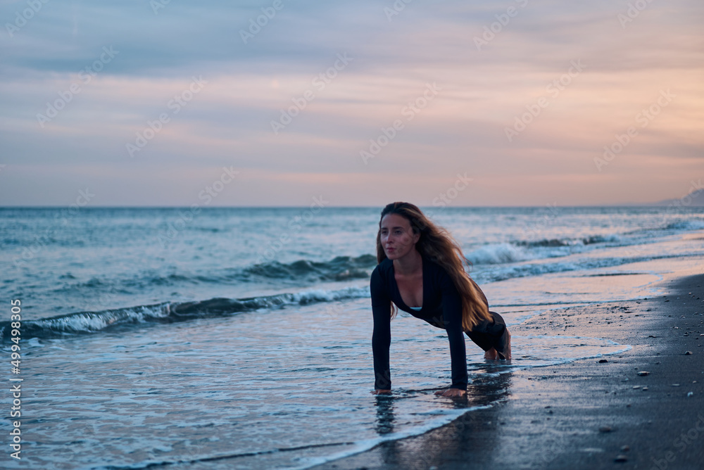 woman doing a yoga practice at the beach while a beautiful sunset