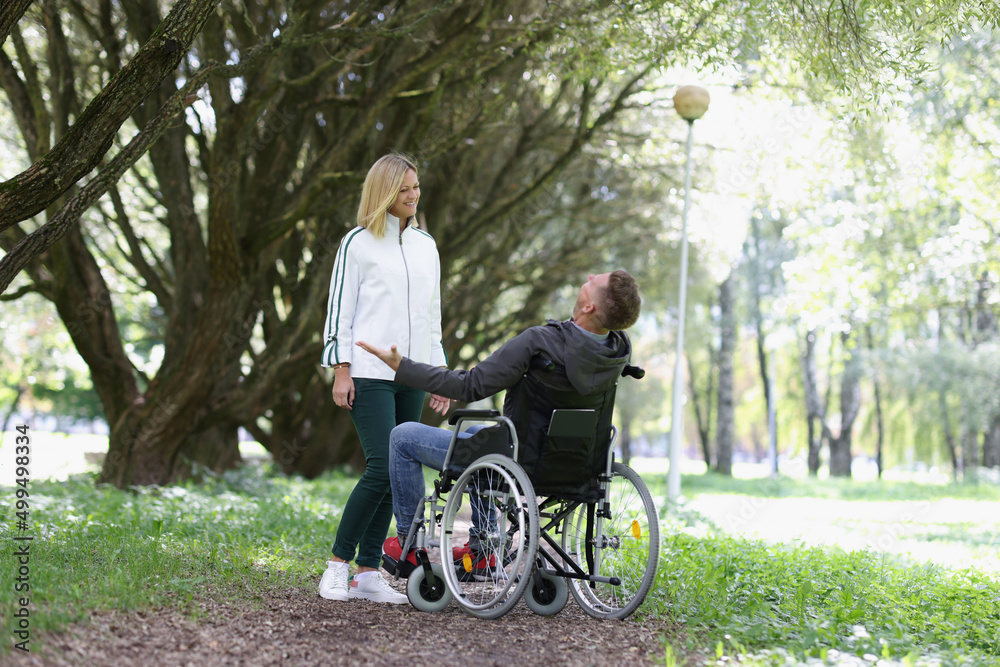 Joyful man in a wheelchair meets woman in park Joyful man in a wheelchair meets woman in park