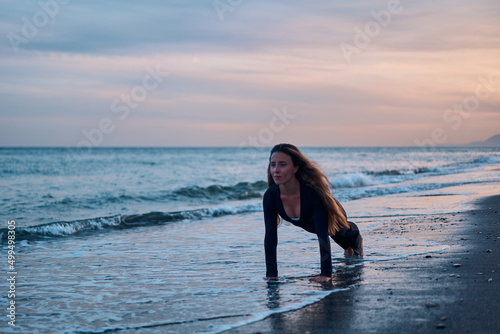 woman doing a yoga practice at the beach while a beautiful sunset