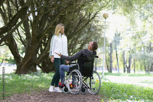 Joyful man in a wheelchair meets woman in park