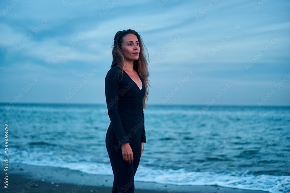 yogui woman standing at the beach while blue hour on sunset yogui woman standing at the beach while blue hour on sunset