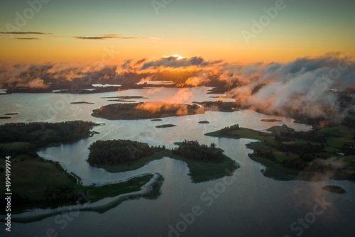 Amazing lake system view from above, islands of various shapes covered with trees and fresh meadows in morning sunlight. Aerial, drone flies over Braslav Lakes National Park on sunrise or sunset