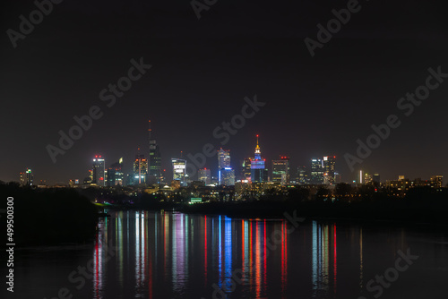 Night in big city of Warsaw skyline  high skyscrapers illumination reflected on Wisla river surface. Downtown beautiful cityscape panorama. Capital of Poland