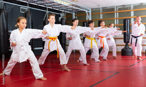 Children wearing karate uniform fighters poses in white kimono, group training