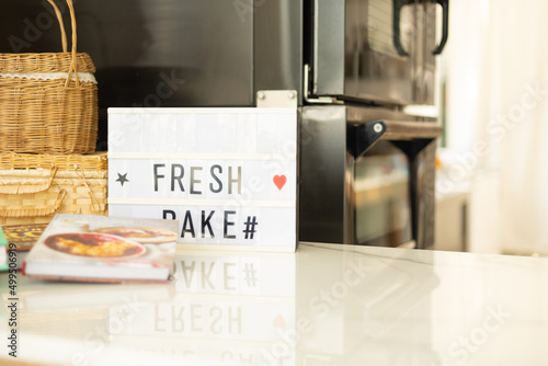 Selective focus with copy space of white and clean marble table top or counter of bright kitchen for bakery with baker oven and nobody for using as beautiful background of restaurant or bakery shop.
