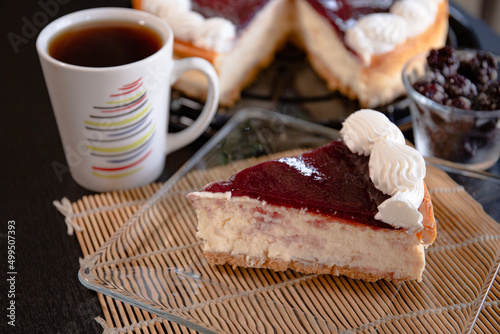 A slice  of cheesecake in a glass plate with a coffe cup  