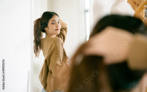 Young beautiful asian woman happily dressed in front of the mirror. She looks good and has confidence in herself photo