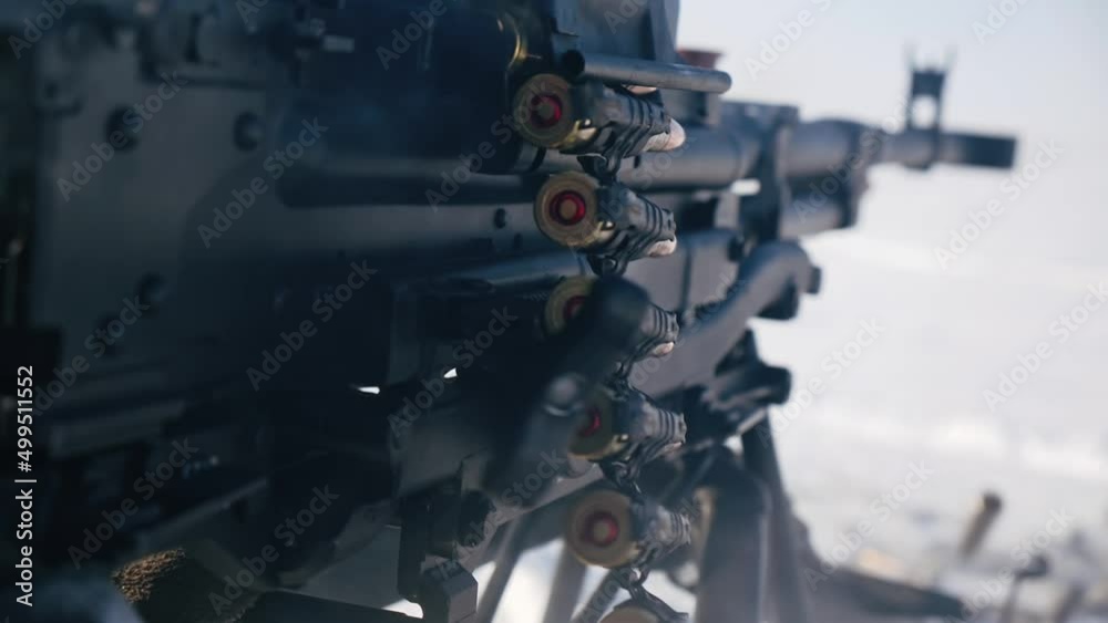 Close-up of a machine gun firing in slow motion. Ejected cartridges fly through the air with visible sparks and smoke, creating a dramatic action scene. Close-up of a machine gun firing in slow motion. Ejected cartridges fly through the air with visible sparks and smoke, creating a dramatic action scene.