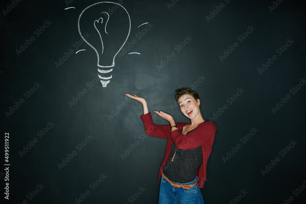 Presenting the solution to your problem. Studio shot of a young woman posing with a chalk illustration of a lightbulb against a dark background.