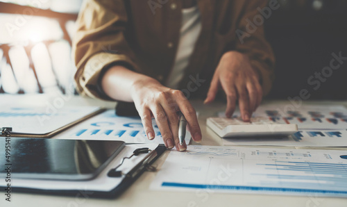 Fotografiet Close up of business woman or accountant working on calculator to calculate busi