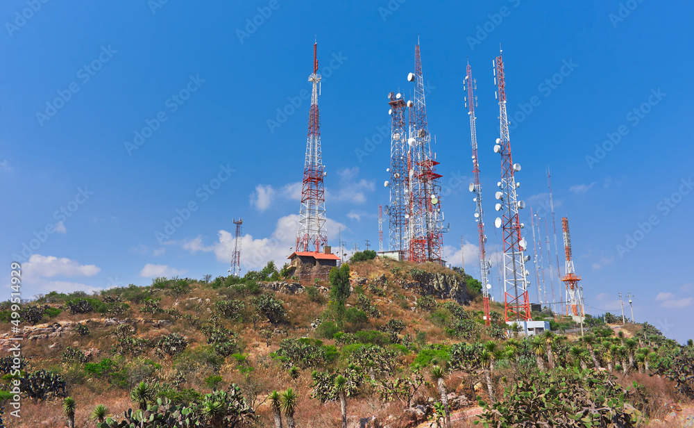 communication towers on top of a mountain in the middle of the desert forest, blue sky in summer day, rocks and palms