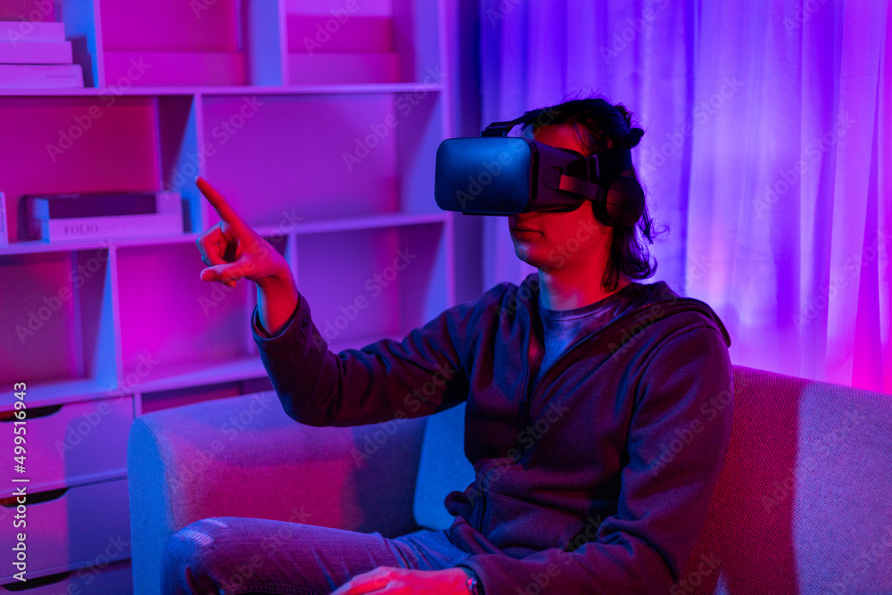 Man wearing virtual reality glasses is playing a 3D game with excitement, Bluetooth Remote Controller, VR, Future games, Gadgets, Technology, Red and blue background, VR game concept. Man wearing virtual reality glasses is playing a 3D game with excitement, Bluetooth Remote Controller, VR, Future games, Gadgets, Technology, Red and blue background, VR game concept.