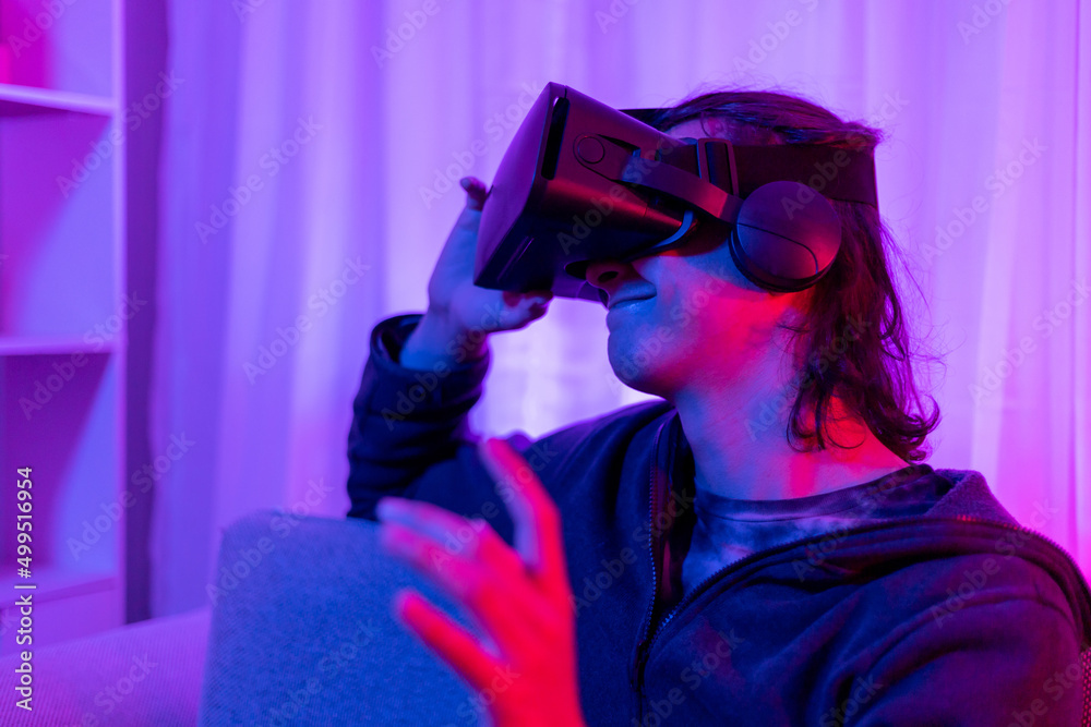 Man wearing virtual reality glasses is playing a 3D game with excitement, Bluetooth Remote Controller, VR, Future games, Gadgets, Technology, Red and blue background, VR game concept. Man wearing virtual reality glasses is playing a 3D game with excitement, Bluetooth Remote Controller, VR, Future games, Gadgets, Technology, Red and blue background, VR game concept.