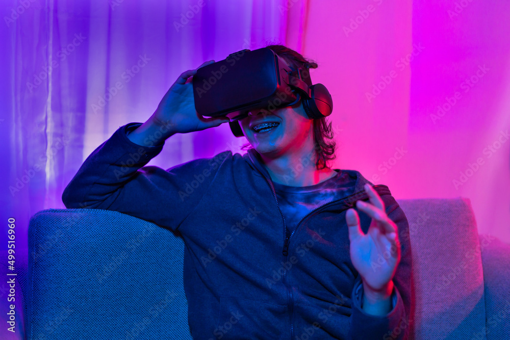 Man wearing virtual reality glasses is playing a 3D game with excitement, Bluetooth Remote Controller, VR, Future games, Gadgets, Technology, Red and blue background, VR game concept. Man wearing virtual reality glasses is playing a 3D game with excitement, Bluetooth Remote Controller, VR, Future games, Gadgets, Technology, Red and blue background, VR game concept.