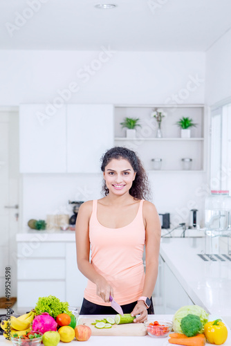 Beautiful woman cutting vegetables in kitchen