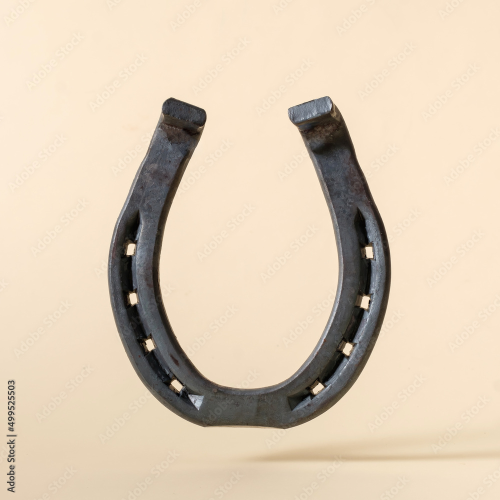 Horseshoe iron on beige background concept of american wild west and rural rodeo or good luck. Horseshoe iron on beige background concept of american wild west and rural rodeo or good luck.
