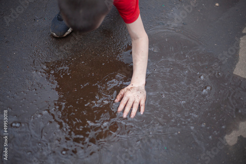 Hand in puddle. Child gets his hand dirty. Boy touches water. Kids love dirt.
