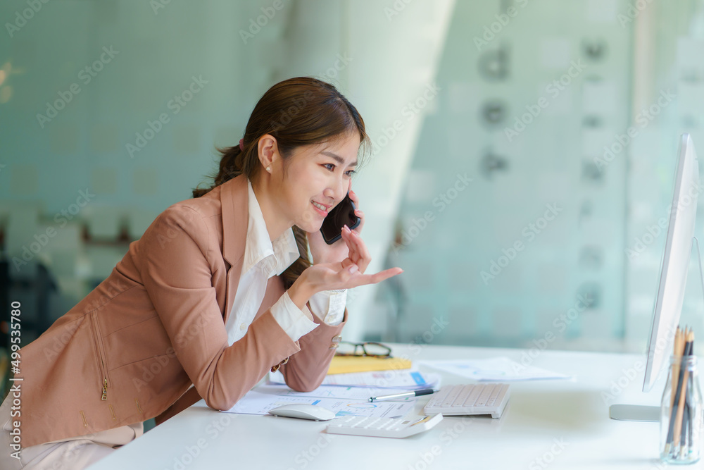 Successful Asian business woman smiling and talking on the phone at the office. Successful Asian business woman smiling and talking on the phone at the office.