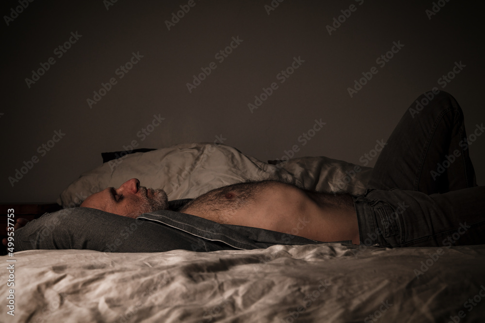 Adult man in open shirt and jeans lying on bed Adult man in open shirt and jeans lying on bed