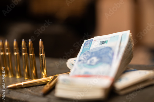 Paper banknotes and rifle cartridges lie on a crate.
