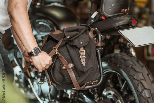 rider install a motorcycle saddlebag or side bag on luggage bracket  vintage motorbike. motorcycle travel concept. selective focus