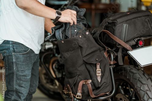 rider take the clothes out of the side bag or saddlebags of motorcycle after trip ,motorcycle travel concept. selective focus