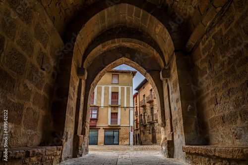 Rustic medieval stone archway in a street in Olite  Spain famous for a magnificent Royal Palace castle on a rainy day with puddles on cobblestones