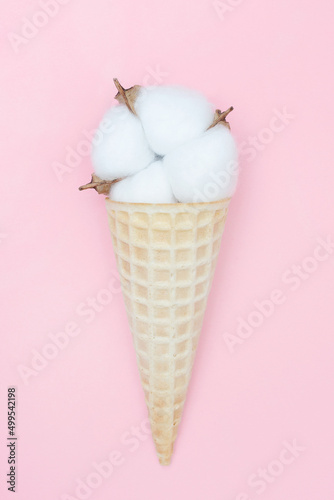 Cotton flower in an ice cream waffle cone. The concept of softness, beauty and taste. Pink background. Blog about life and style. Vertical. Flat lay. Top view.