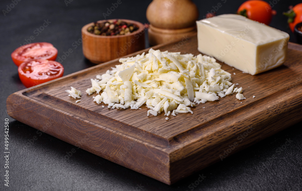 Image of a bar and grated mozzarella cheese on a dark background Image of a bar and grated mozzarella cheese on a dark background