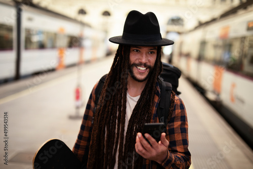 Handsome guy at railway station waiting for the train. Young man waiting to board a train. Urban guy using the phone. photo