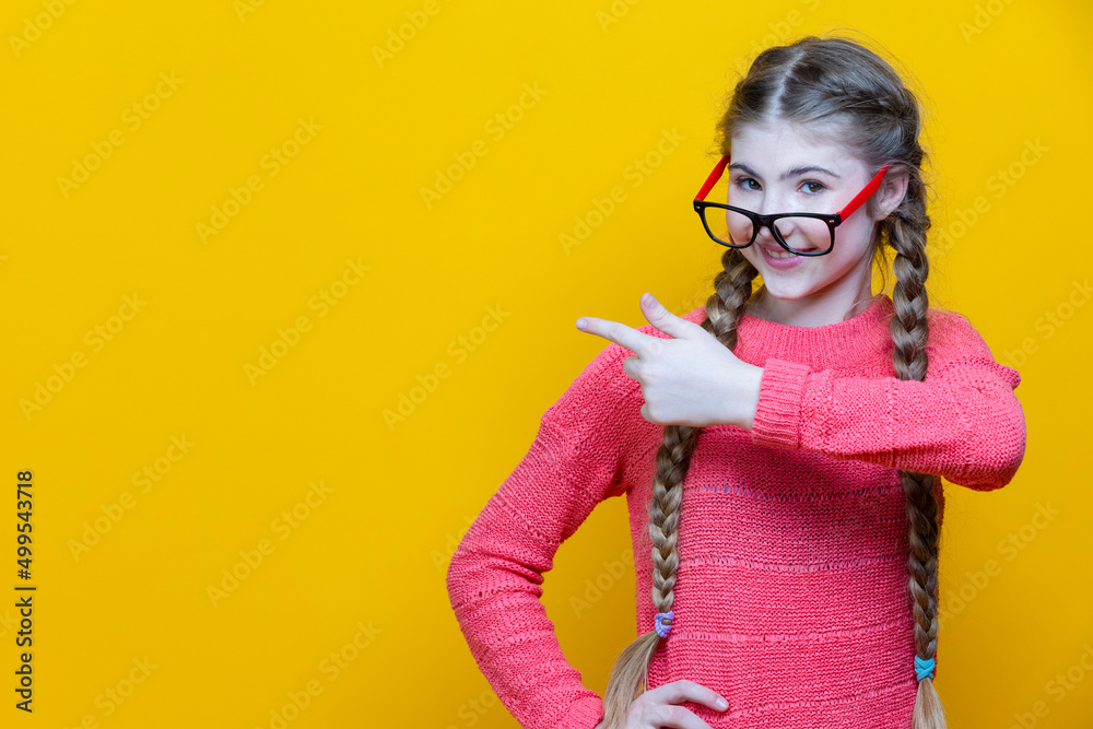 Portrait of Caucasian Teenage Girl in Red Glasses Pointing to Side Over Yellow Portrait of Caucasian Teenage Girl in Red Glasses Pointing to Side Over Yellow