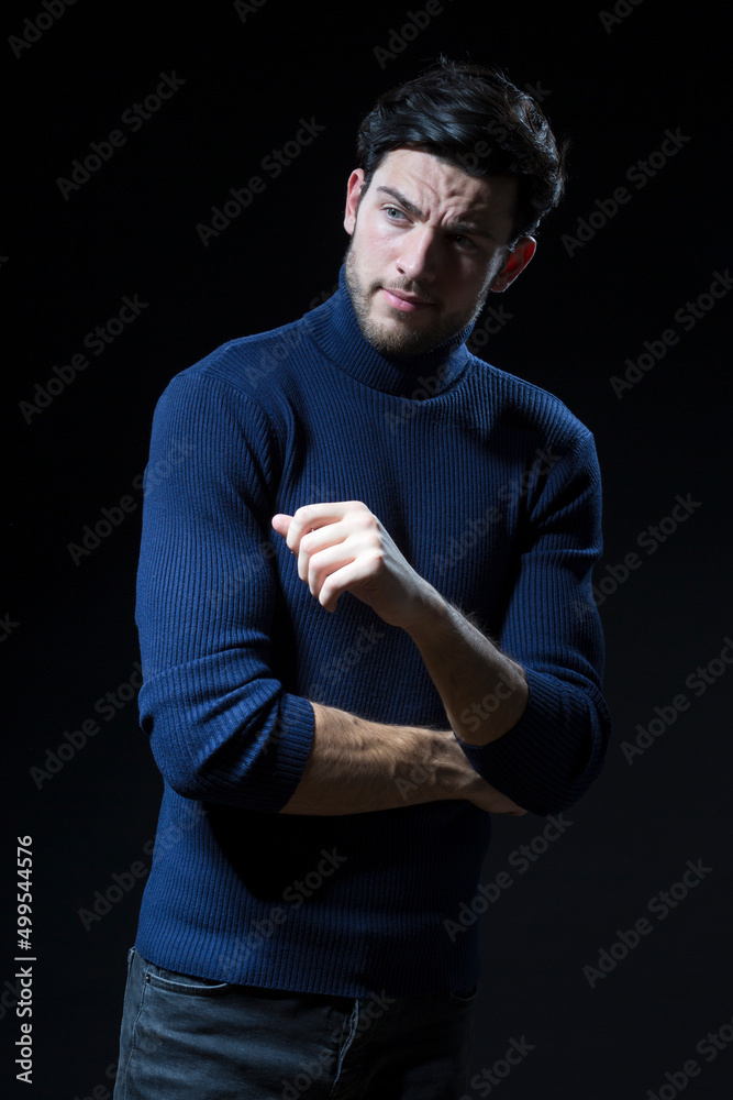 Handsome Brunet Man Posing in Blue Turtle Neck Sweater With Folded Hands Against Black Background With Copy Space as Successful Young Man Handsome Brunet Man Posing in Blue Turtle Neck Sweater With Folded Hands Against Black Background With Copy Space as Successful Young Man