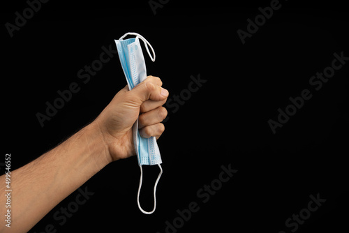hand of a man squeezing a blue face mask