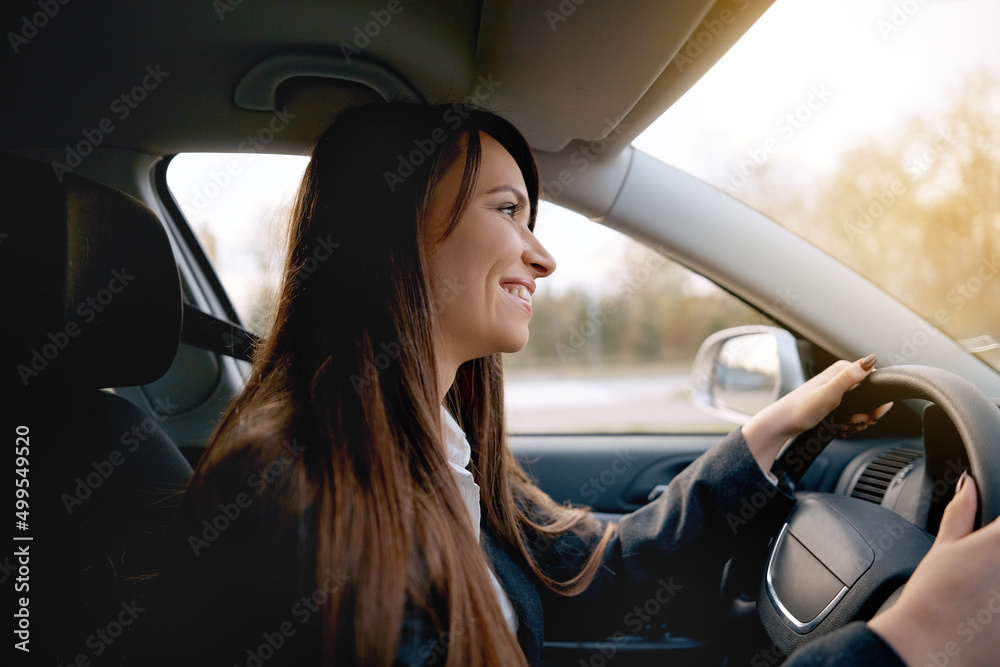 Beautiful young happy smiling woman driving her new car