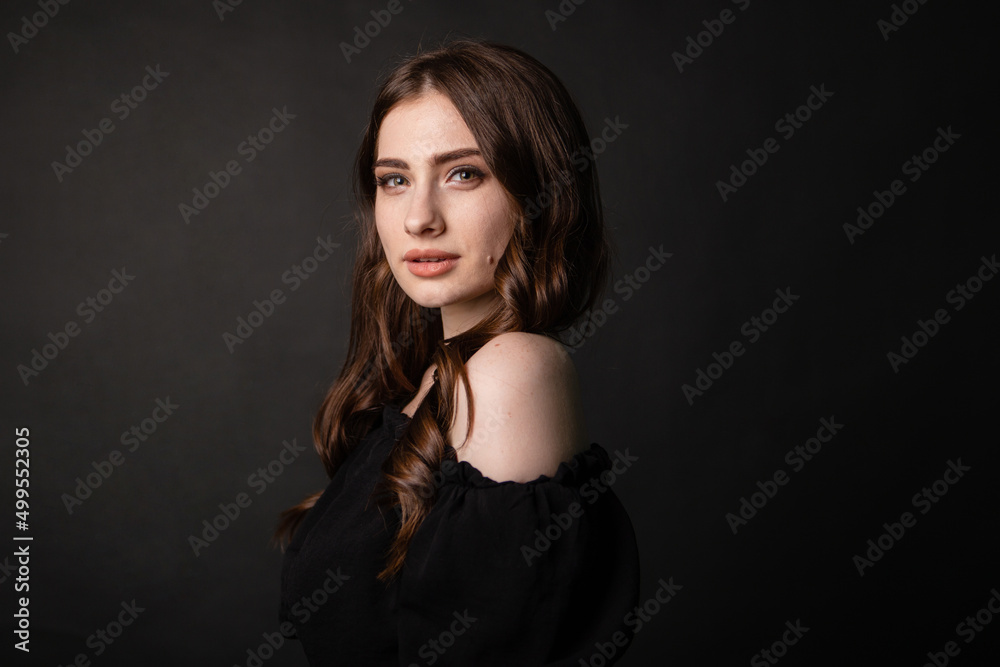 Portrait of a beautiful woman with long hair on a dark background.Girl with a charming smile.