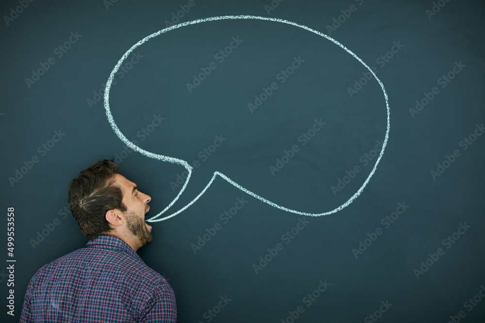 Im getting this off my chest. Shot of a young man standing in front of a blackboard with a speech bubble drawn on it.