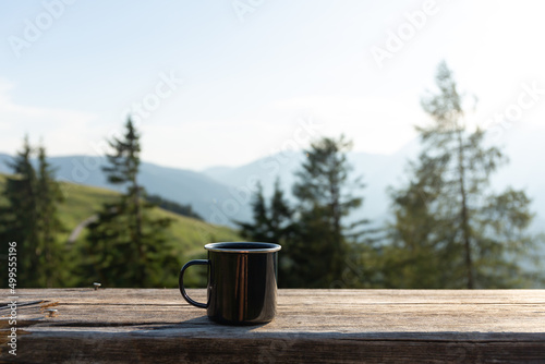 Camping mug on the wooden railing on the mountains background in Austrian Alps 