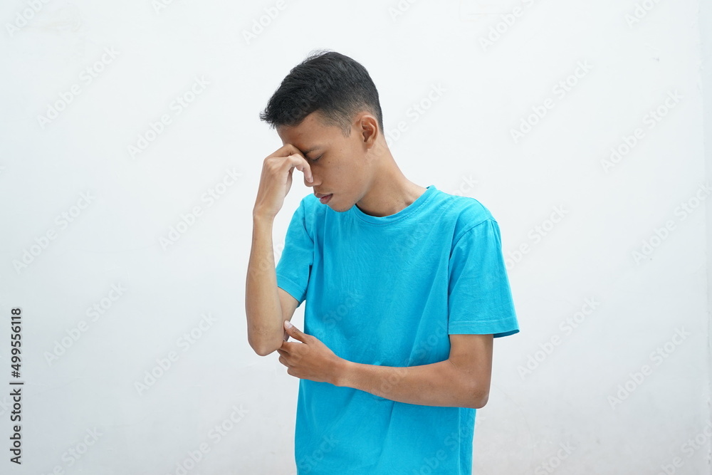 Runny nose or sinusitis concept. Asian man wearing blue t-shirt holding bridge of nose and suffering in pain Runny nose or sinusitis concept. Asian man wearing blue t-shirt holding bridge of nose and suffering in pain