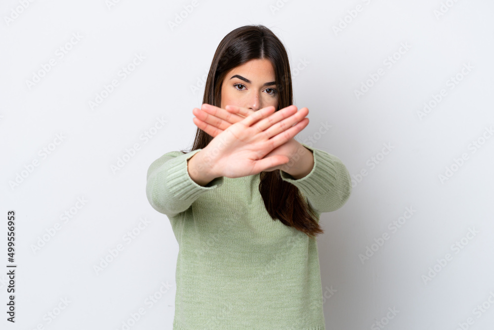 Young Brazilian woman isolated on white background making stop gesture with her hand to stop an act Young Brazilian woman isolated on white background making stop gesture with her hand to stop an act