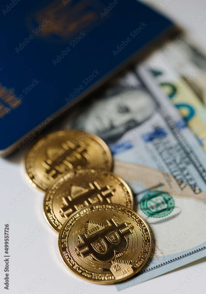 Urkainian passport with bitcoin golden coins and different banlnotes. US dollars and euro cash near the passport. Urkaine currency during the war Urkainian passport with bitcoin golden coins and different banlnotes. US dollars and euro cash near the passport. Urkaine currency during the war