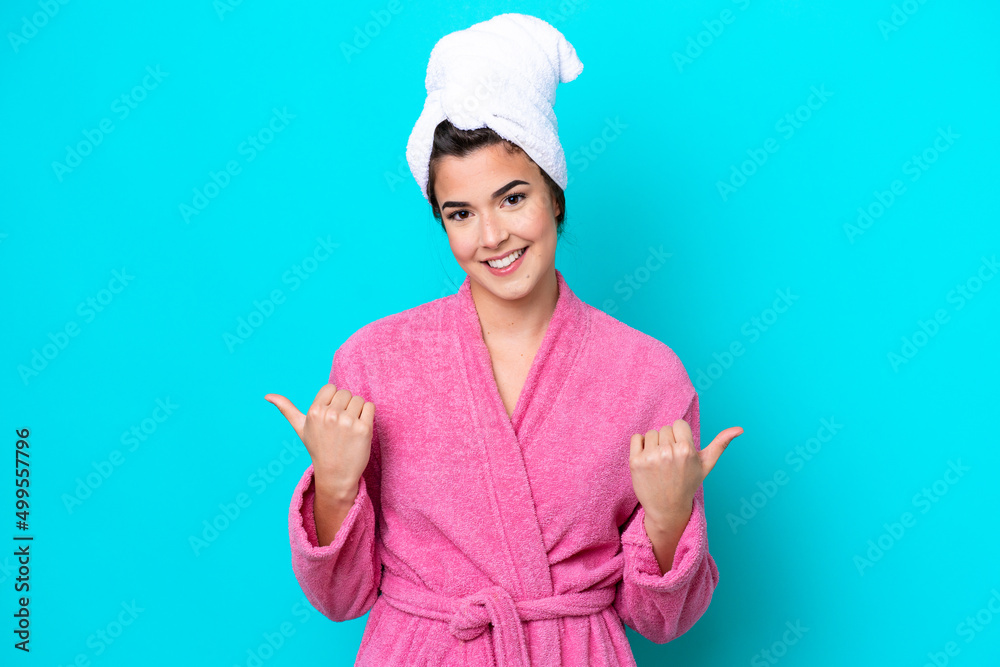 Young Brazilian woman with a bathrobe isolated on blue background with thumbs up gesture and smiling Young Brazilian woman with a bathrobe isolated on blue background with thumbs up gesture and smiling