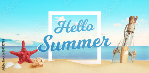 Hello summer text on beach sand surrounded by sea star, shells and message in the bottle. Tropical vacation concept