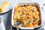 Baked potato gratin with cheese and thyme in oven dish, gray background.