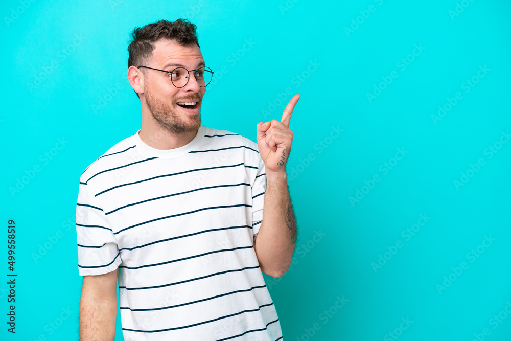 Young Brazilian man isolated on blue background intending to realizes the solution while lifting a finger up Young Brazilian man isolated on blue background intending to realizes the solution while lifting a finger up
