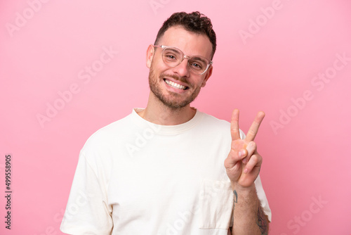 Young brazilian man isolated on pink background With glasses and doing OK sign